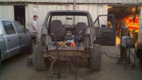 1989 Ford Bronco - This 1989 Ford Bronco is in a workshop, with a pickup truck parked beside it and welding equipment nearby.