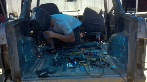 1989 Ford Bronco - A person is welding inside the rear of a vehicle that appears to be undergoing restoration or modification.