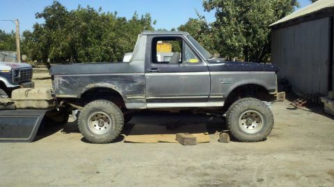1989 Ford Bronco - Side view of a 1989 Ford Bronco, with another vehicle visible in the background.