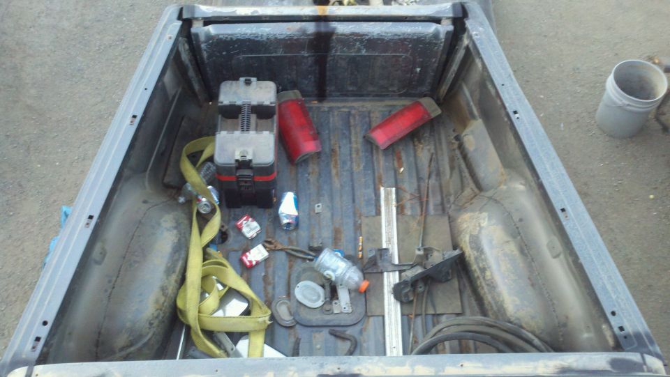 Truck bed with red taillights, a toolbox, and a yellow strap