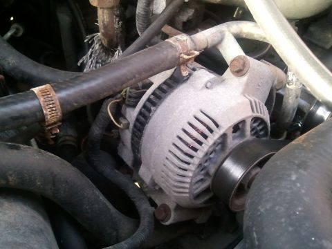 1994 Ford Bronco - Close-up view of a vehicle's alternator and surrounding engine components.