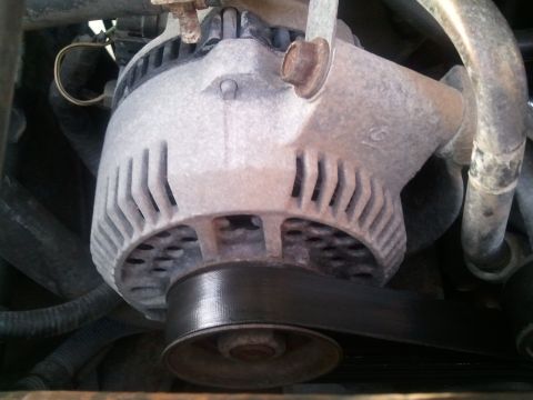 1994 Ford Bronco - Close-up view of a vehicle's alternator and drive belt system.