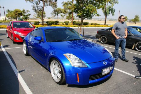 1995 Ford Taurus - A blue Nissan 350Z is parked in a lot next to other vehicles on a sunny day.