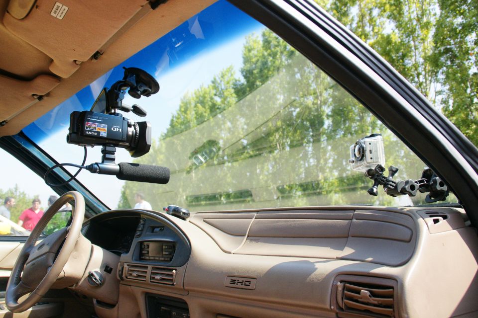 Car interior showing dashboard, steering wheel, and two cameras mounted on the windshield