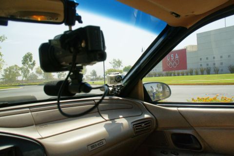 1995 Ford Taurus - View from inside a car, equipped with cameras, looking out towards a building with the Olympic rings logo.