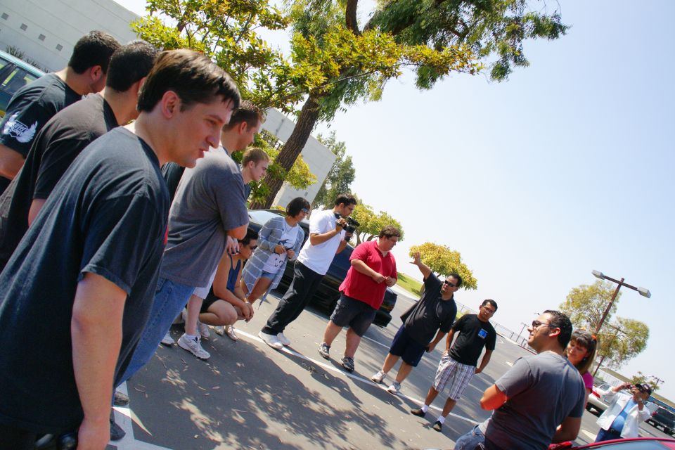 Group of people standing and talking in a sunny outdoor parking lot