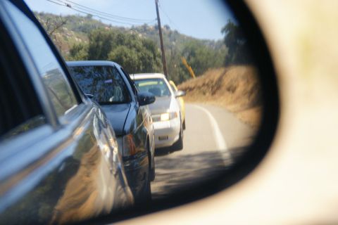 1995 Ford Taurus - A 1995 Ford Taurus is visible in the side mirror of another vehicle, traveling on a winding road.