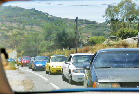 1995 Ford Taurus - A line of cars are driving down a rural road on a sunny day.