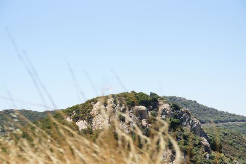 1995 Ford Taurus - A landscape scene with rocky hills and vegetation under a bright blue sky.