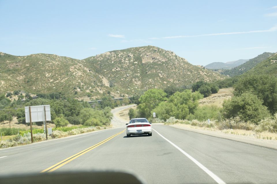 White 1995 Ford Taurus driving on a highway with mountains in the background