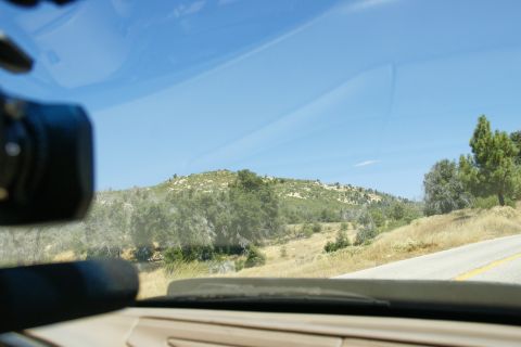 1995 Ford Taurus - View from inside a vehicle looking out at a sun-drenched, arid landscape with rolling hills and sparse vegetation.