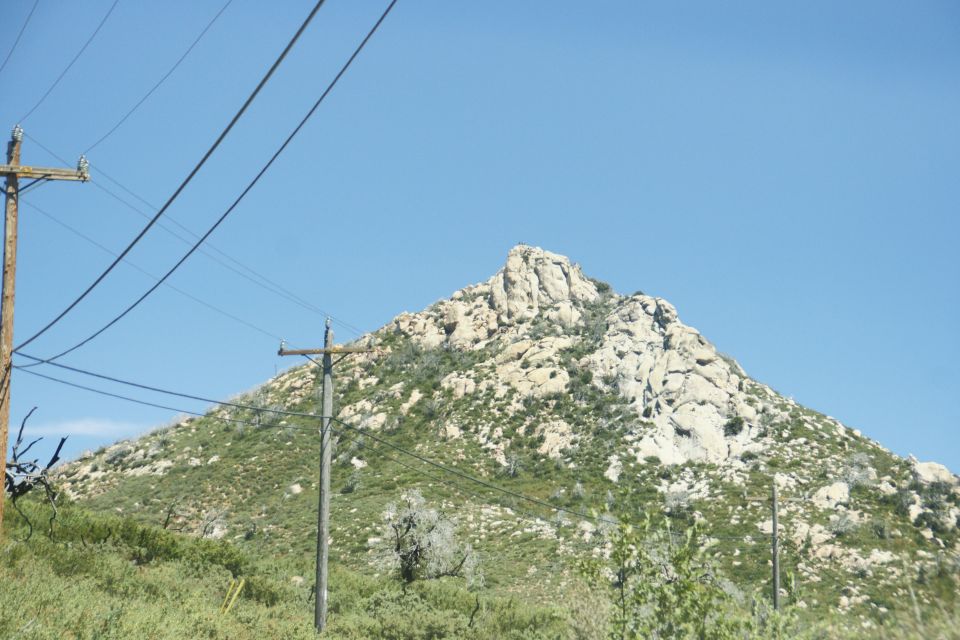 Rocky mountain peak under a clear blue sky with telephone poles and wires in the foreground