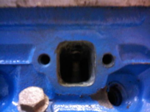 1997 Ford Ranger - Close-up of a blue engine block component with a central square opening and surrounding bolt holes.