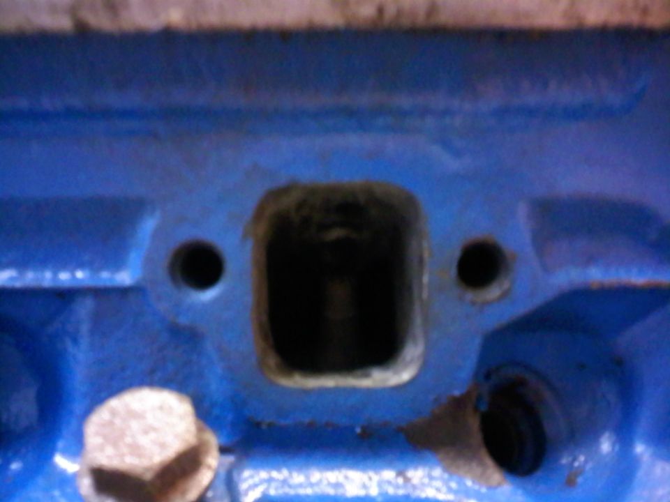 Blue painted engine block with a square intake port and two bolt holes