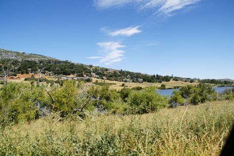 1995 Ford Taurus - A wide view of a rural landscape a lake, hills, and houses, with dry vegetation in the foreground.