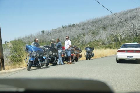 1995 Ford Taurus - Group of motorcycles and a car on a roadside with a dry, wooded hillside.
