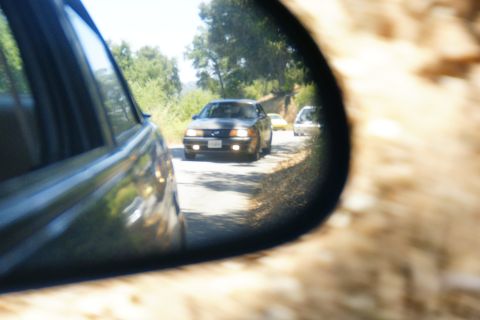 1995 Ford Taurus - View of traffic on a road through a car's side mirror, showing a 1995 Ford Taurus.