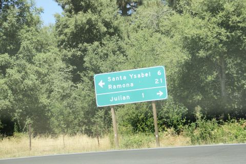 1995 Ford Taurus - A green road sign indicates distances to Santa Ysabel, Ramona, and Julian, set against a backdrop of trees.
