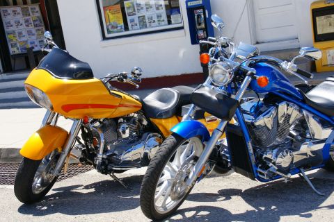 1995 Ford Taurus - Two motorcycles are parked side-by-side on a sunny day in front of a building.