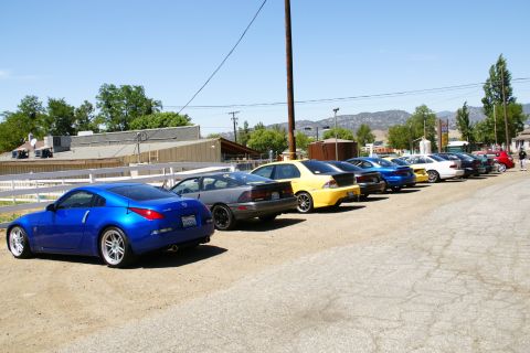 1995 Ford Taurus - A row of cars are parked on a dirt lot under a clear blue sky.