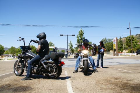 1995 Ford Taurus - Two motorcycles are parked on a sunny day with two riders and a third person standing.