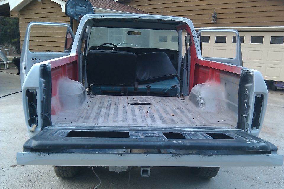 Rear view of a 1978 Ford Bronco with doors open and tailgate down, showing the interior and bed