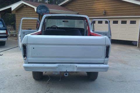 1978 Ford Bronco - A gray 1978 Ford Bronco is parked in a driveway with its doors open, showing its primer finish and tow hitch.
