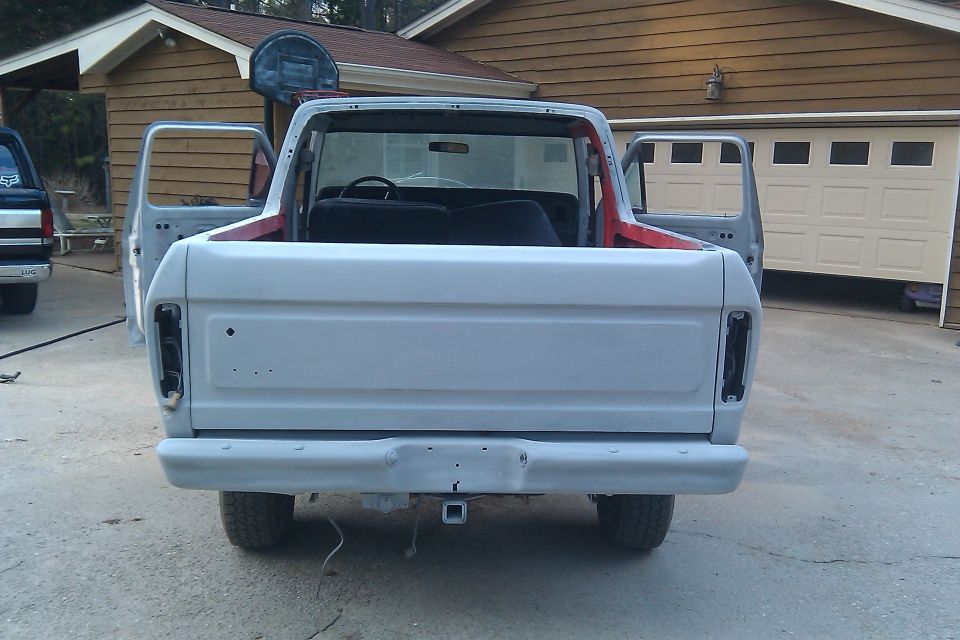 Gray 1978 Ford Bronco rear view, doors open, primer finish, tow hitch