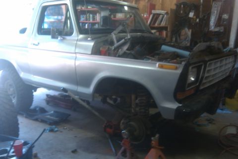 1978 Ford Bronco - A silver 1978 Ford Bronco is shown in a garage with its hood open, indicating it is undergoing maintenance or repair.