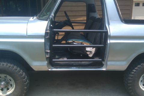 1978 Ford Bronco - This 1978 Ford Bronco is shown from the side with its door open, revealing a roll cage and interior.