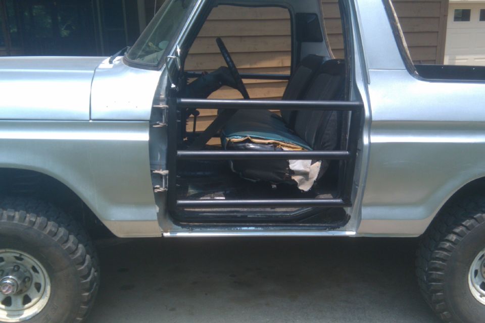 Silver 1978 Ford Bronco side view with roll cage and open door