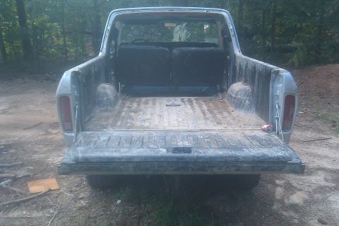 1978 Ford Bronco - The rear of a 1978 Ford Bronco is shown with the tailgate open, revealing the cargo area and seats.