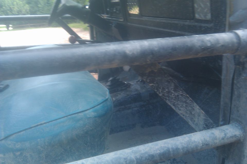 Inside of a dirty vehicle, showing a blue seat, roll cage, and steering wheel