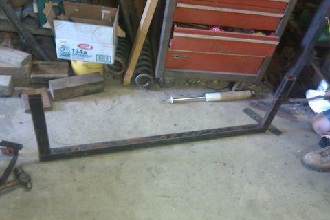 1978 Ford Bronco - Metal frame and shock absorber in a workshop setting with a red toolbox.