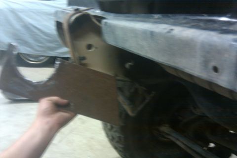 1978 Ford Bronco - A person is holding a metal part near the frame of a vehicle, suggesting a repair or modification is underway.