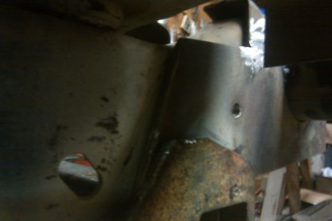 1978 Ford Bronco - Close-up of a rusty vehicle frame part, showing welds and a hole.