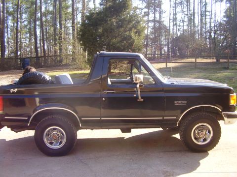 1988 Ford Bronco - Side view of a 1988 Ford Bronco with a spare tire visible in the open rear.