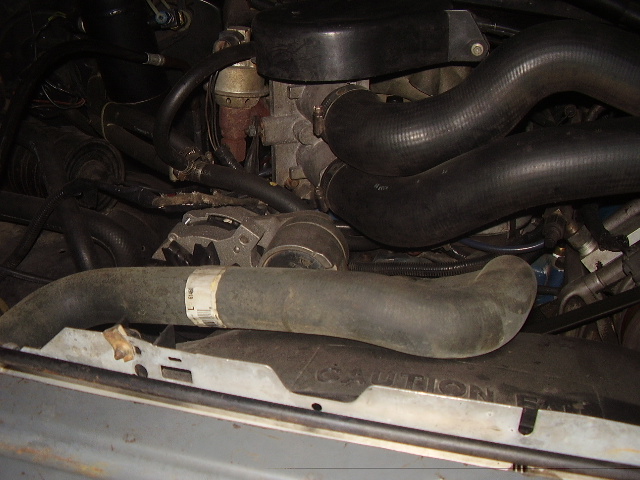 Engine bay detail showing hoses, alternator, and carburetor