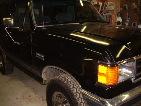 1988 Ford Bronco - The front quarter panel of a black Ford Bronco is visible, parked indoors.