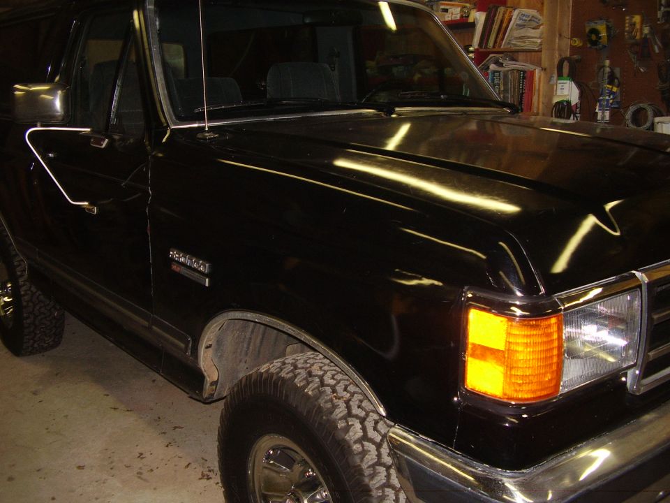 Black Ford Bronco parked in garage, showing front fender and door