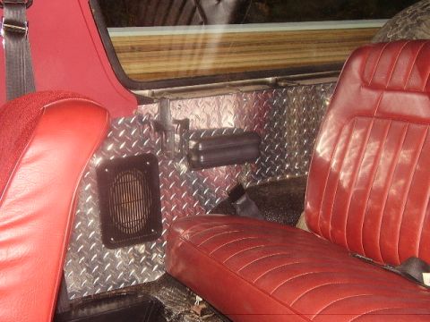 1986 Ford Bronco - Interior view shows red seats and diamond plate paneling on the vehicle's side.