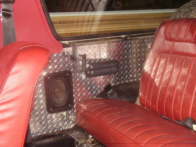 Interior view of red seats and diamond plate paneling on the side of a vehicle