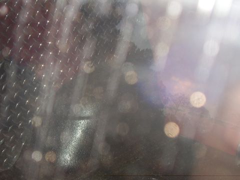 1986 Ford Bronco - A close-up of a textured metal surface with out-of-focus lights and reflections.