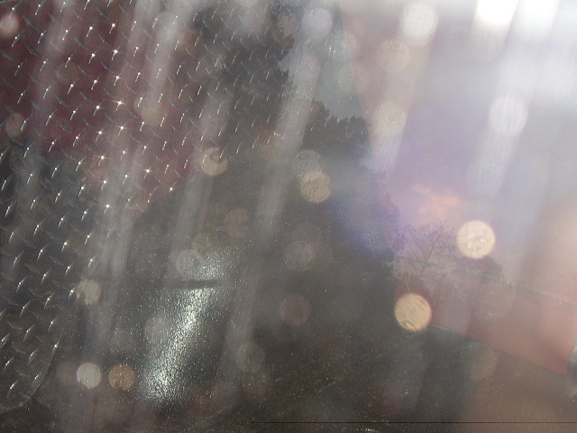 Diamond plate metal surface with bokeh lights and a reflection of a dark object