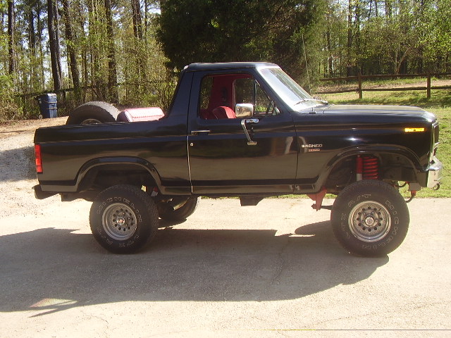 Black 1986 Ford Bronco side view with lifted suspension and red interior