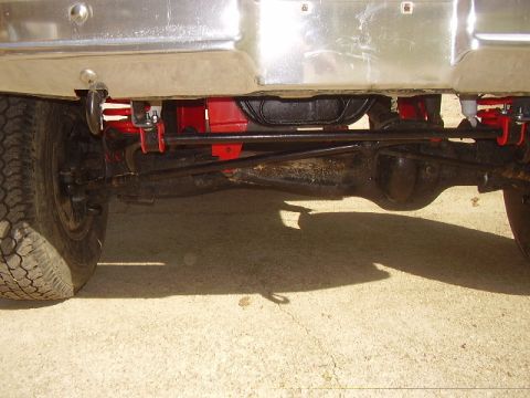 1986 Ford Bronco - Close-up shot of the vehicle's rear axle and suspension system, with a chrome bumper overhead.
