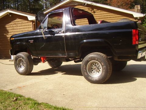 1986 Ford Bronco - This black 1986 Ford Bronco is shown from a 3q front angle, with the "Bronco" badge clearly visible on the fender.