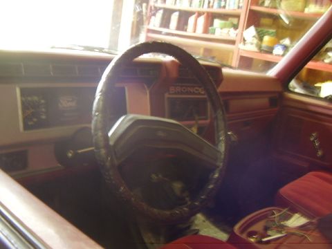 1986 Ford Bronco - The interior of a 1986 Ford Bronco shows red seats and a dashboard with the Bronco nameplate visible.