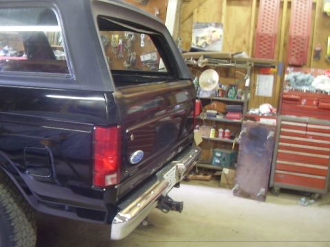 1986 Ford Bronco - Rear view of a black Ford Bronco in a workshop setting.