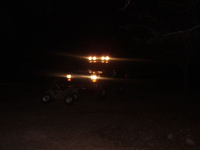 SUV with roof lights and ATV at night